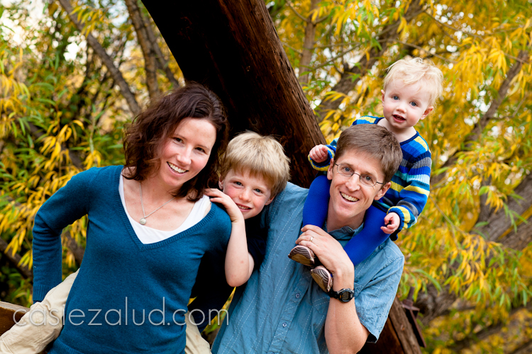 family portrait on a bridge with fall colors in the background