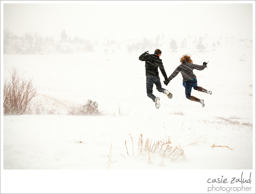 engaged couple jumping in a snowstorm in Boulder