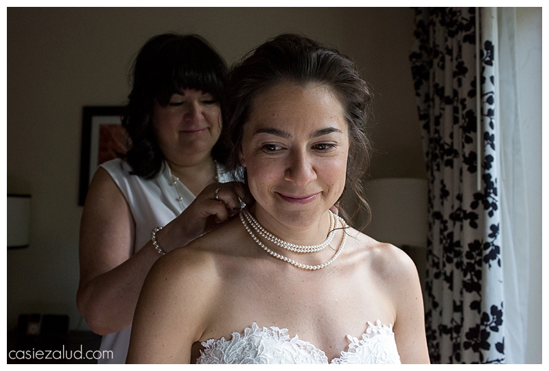 mother putting pearls on her daughter's neck as she gets ready for her wedding