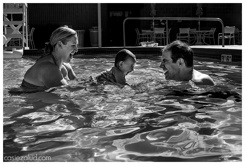 Mom and dad passing a toddler back and fourth in a pool