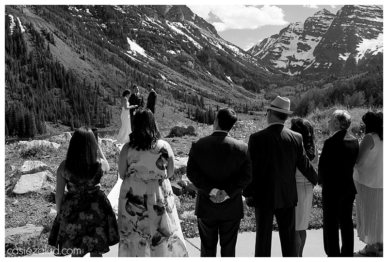shot from the back seats of the amphitheater at the Maroon Bells overlooking the guests and looking at the bride and groom and Maroon Bells