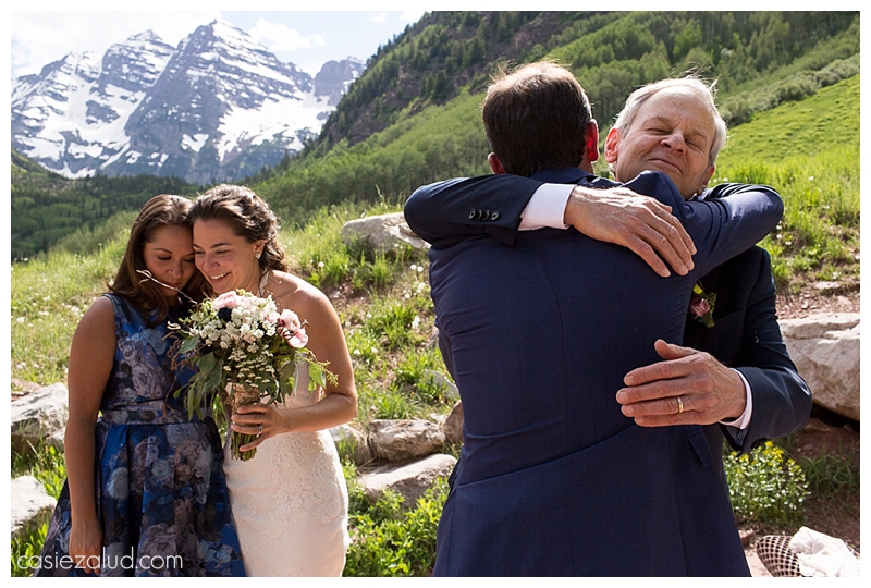 groom hugging dad while bride hugs sister in law at their maroon Bells wedding