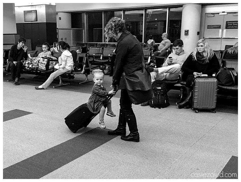 mom pulling a toddler on a suitcase in an airport