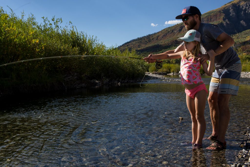 girl and father fly fishing in bathing suits in Aspen during a colorado family photography vacation session