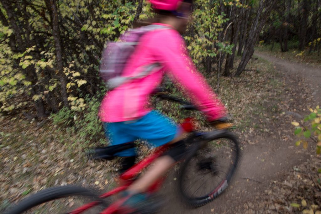 panning image of girl in pink riding mountain bike downhill