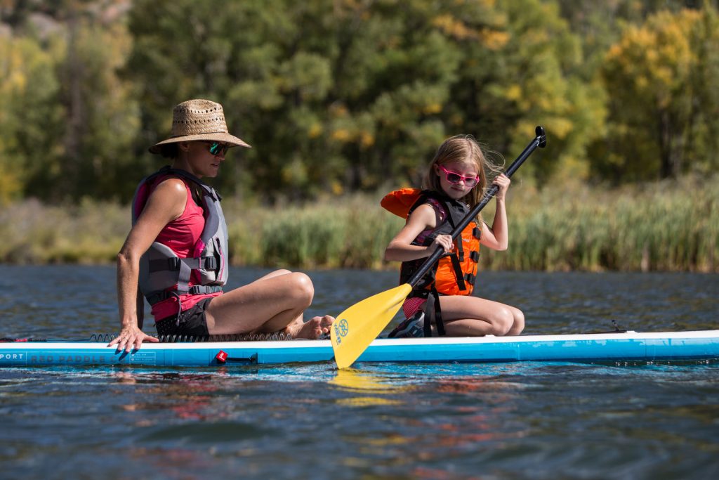 mom and daughter paddling on a SUP on Beaver Lake during a vacation photography session
