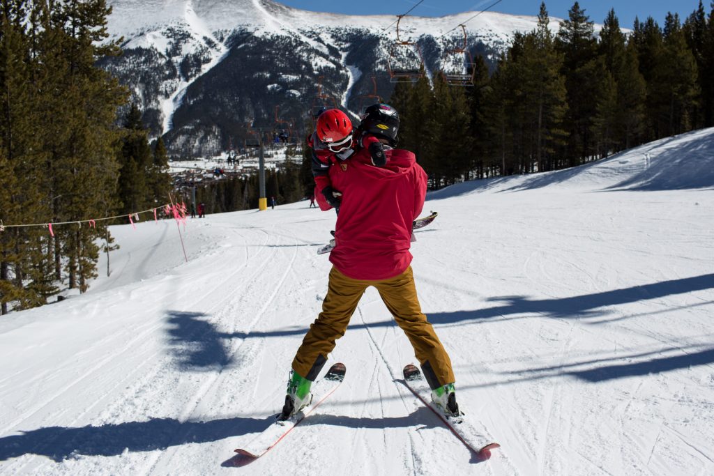 dad skiing down the hill carrying child at copper mountain