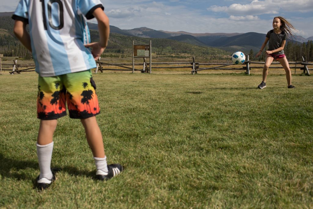 two kids playing soccer on the lawn at devils thumb during a family photography session